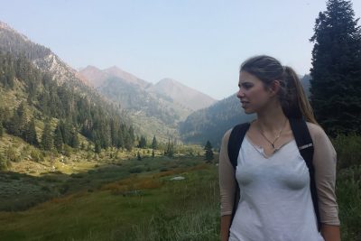 Skylar Moiseeva standing in front of a mountain scene.